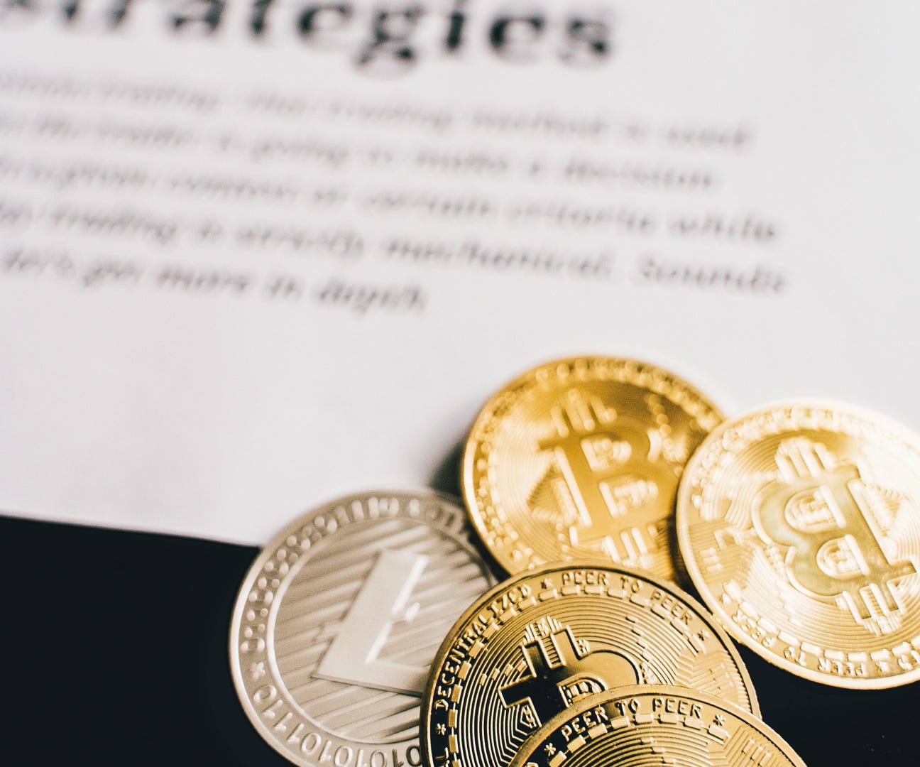 Close-up of Bitcoin and Litecoin coins on a trading strategies document.